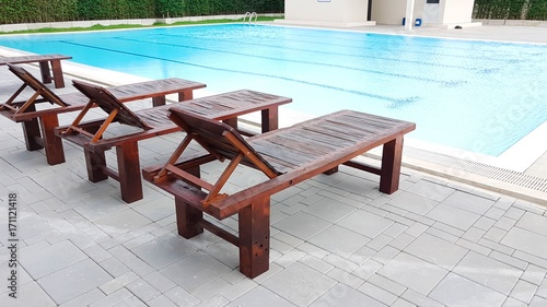 Brown wooden foldable bed beside the swimming pool