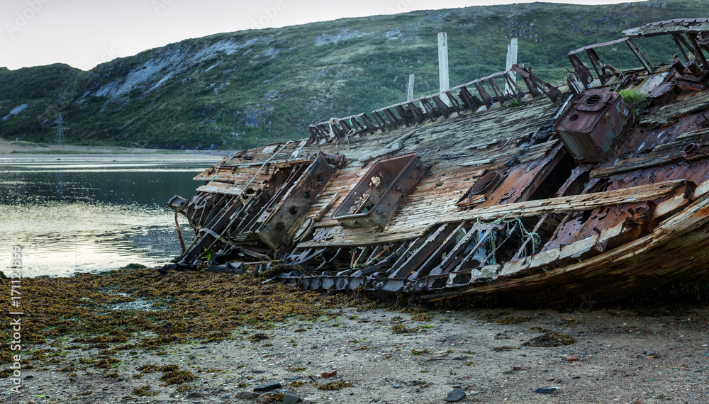 Old wooden abandoned ship stands on a sandy beach in beautiful nature