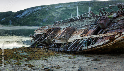 Old wooden abandoned ship stands on a sandy beach in beautiful nature