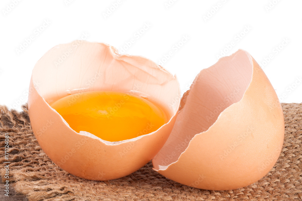 Broken egg with yolk and eggshell on a wooden table with a white background Broken egg with yolk and eggshell on a wooden table with a white background