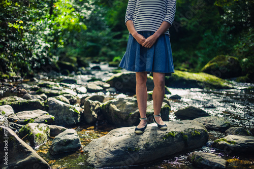Woman in skirt standing on rocks in river