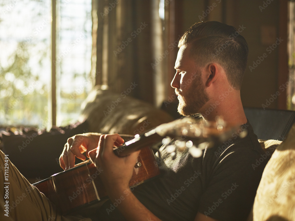 Fototapeta premium man playing guitar on sofa at home