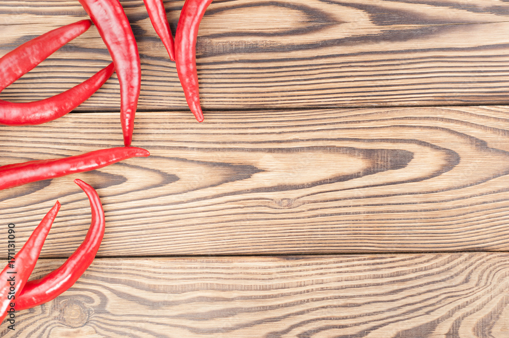 Scattered wholes red fresh ripe chili pepper on old brown wooden rustic planks Scattered wholes red fresh ripe chili pepper on old brown wooden rustic planks