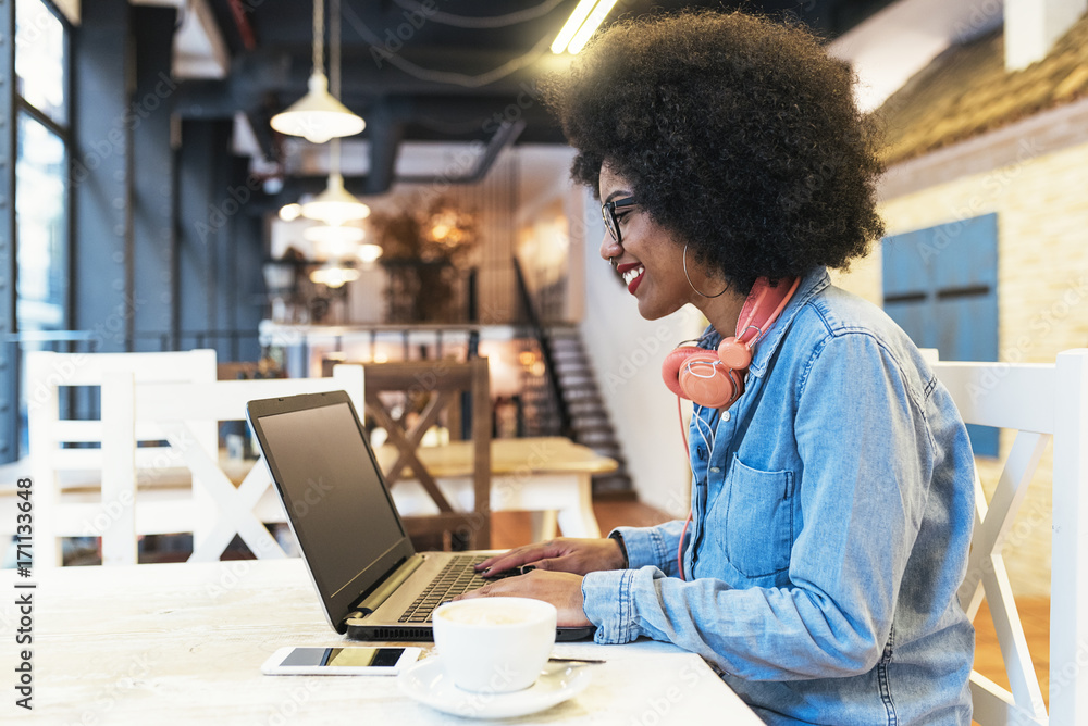 © santypan - Beautiful afro american woman using mobile and laptop in the coffee shop. © santypan - Beautiful afro american woman using mobile and laptop in the coffee shop.