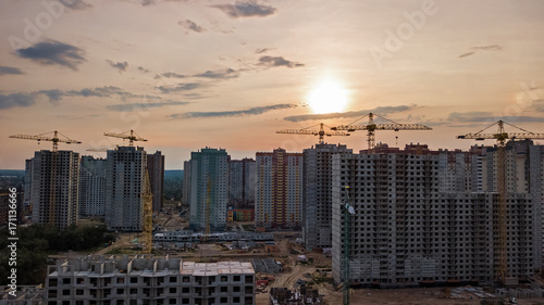 Aerial view of construction site of residential area buildings with cranes at sunset from above, urban skyline of Kyiv city, Ukraine 