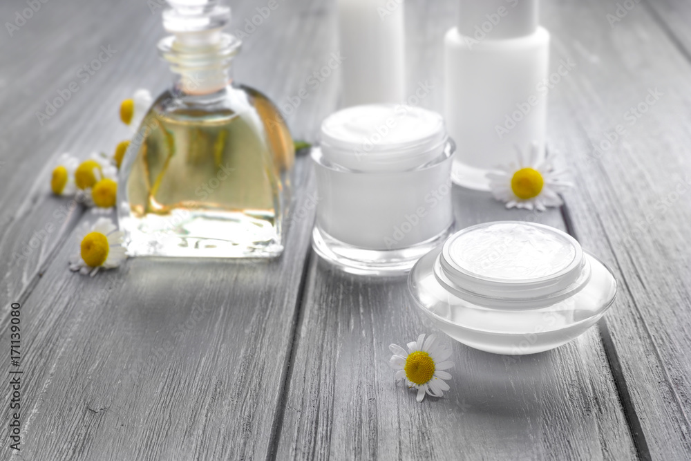 Cosmetic products and fresh chamomile flowers on wooden table Cosmetic products and fresh chamomile flowers on wooden table