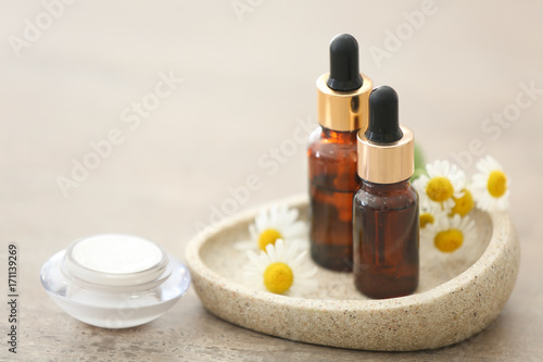 Cosmetics with chamomile extract on light background