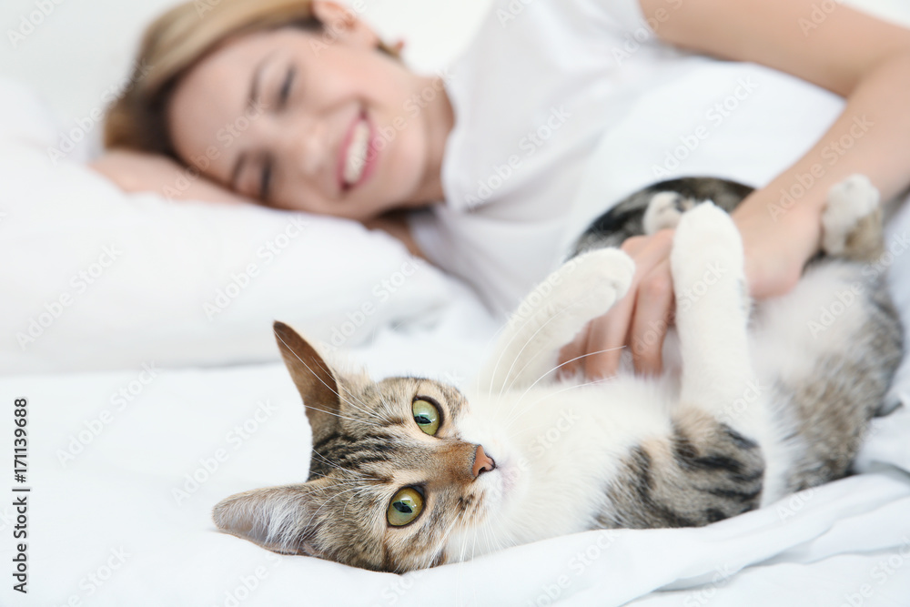Young beautiful woman with cat lying on bed at home Young beautiful woman with cat lying on bed at home