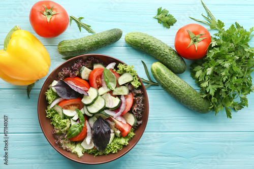 Vegetable salad with cucumbers in bowl on table