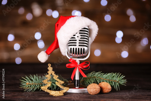 Christmas music concept. Microphone with hat and decoration on wooden table photo