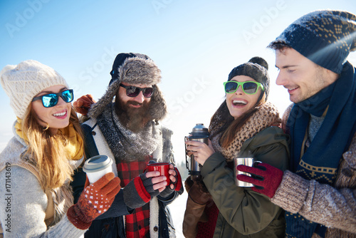 Two couples drinking warm tea from vacuum bottle