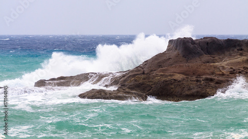 Big wave crashing about the huge rock and made white foam.