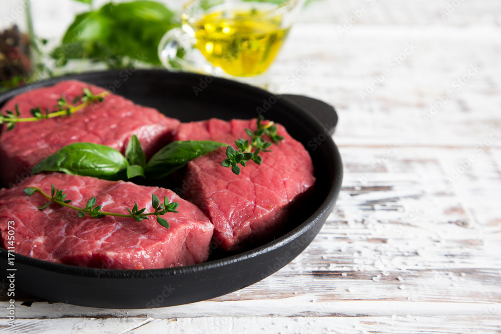 raw beef steak on a light wooden background with olive oil and spices raw beef steak on a light wooden background with olive oil and spices