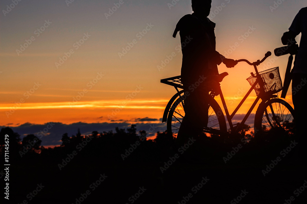 man with a bicycle at sunset.