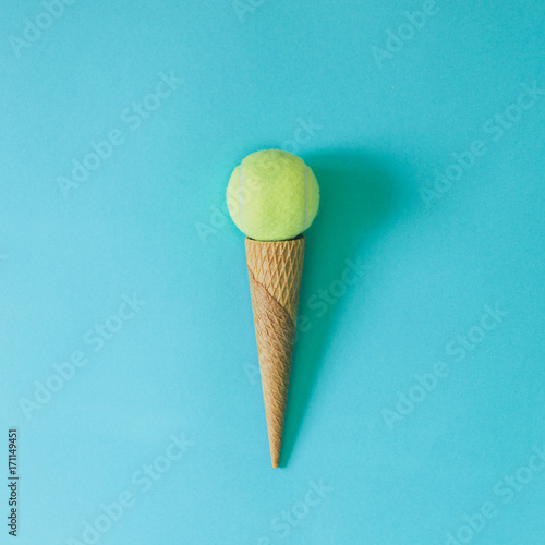 Ice cream cone with tennis ball on bright blue background. Minimal food concept.