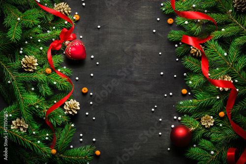 Christmas and New Year background. Christmas tree branch on a black background. Cones and fur-tree toys. View from above. photo