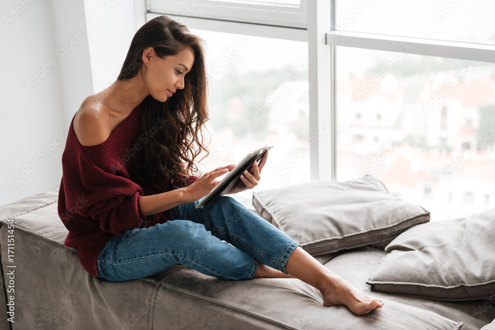 Smiling pretty woman in sweater using tablet computer Smiling pretty woman in sweater using tablet computer