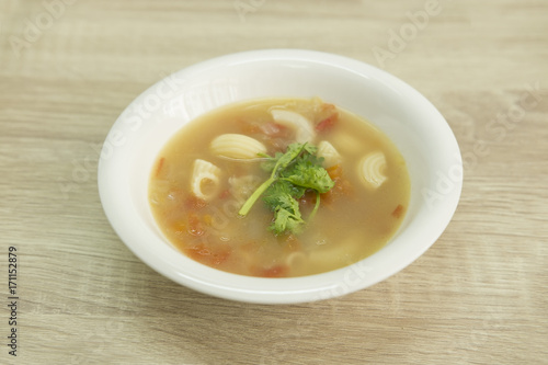 BONE BROTH TOMATO SOUP WITH MACARONI
Bone broth tomato soup with  macaroni in a white bowl decorated with green coriander. 