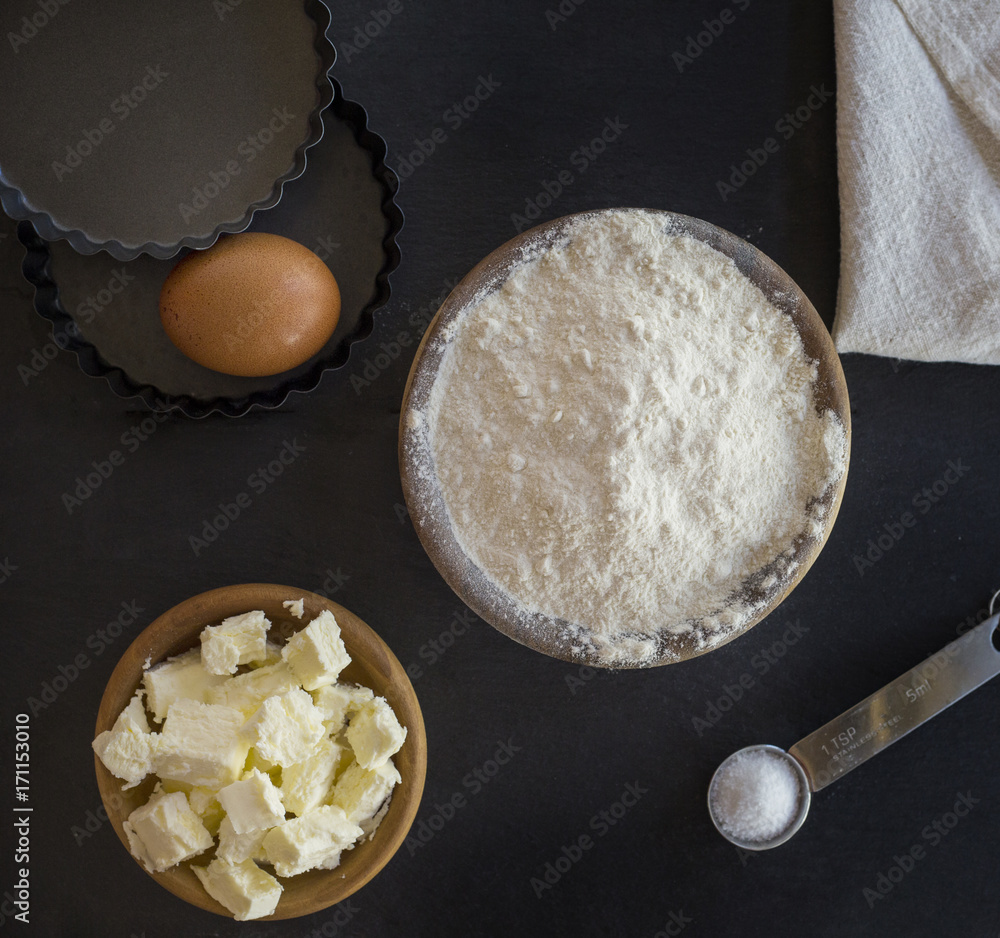 flour and ingredients on black table. Top view - obrazy, fototapety, plakaty 