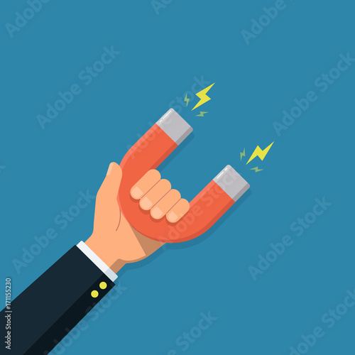 Hand of a businessman with magnet. Business concept of the attraction of money, customers and investment.