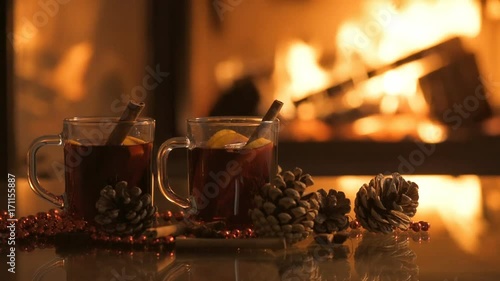 Mulled wine glasses on table in front of burning fireplace.