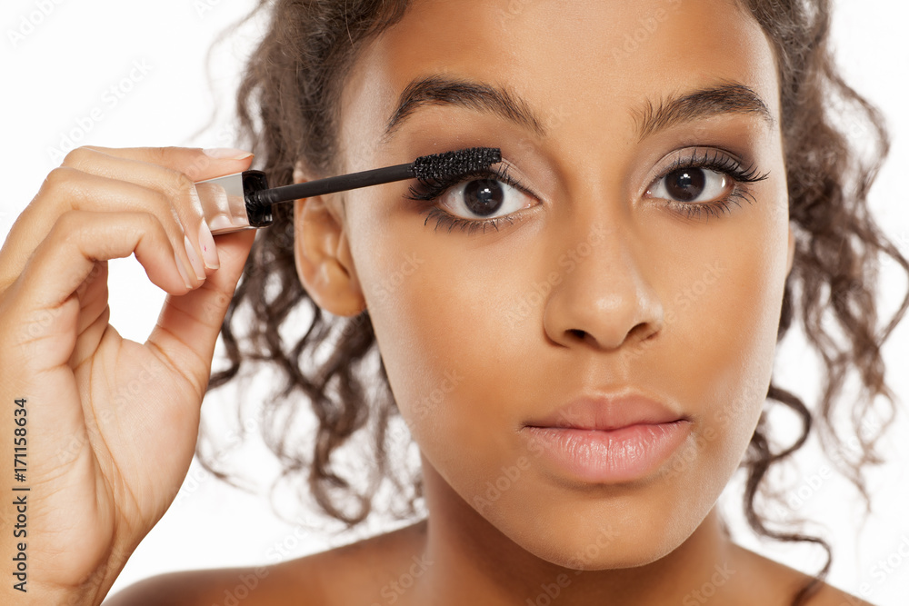 a young dark skinned woman applying a mascara to her eyelashes a young dark skinned woman applying a mascara to her eyelashes