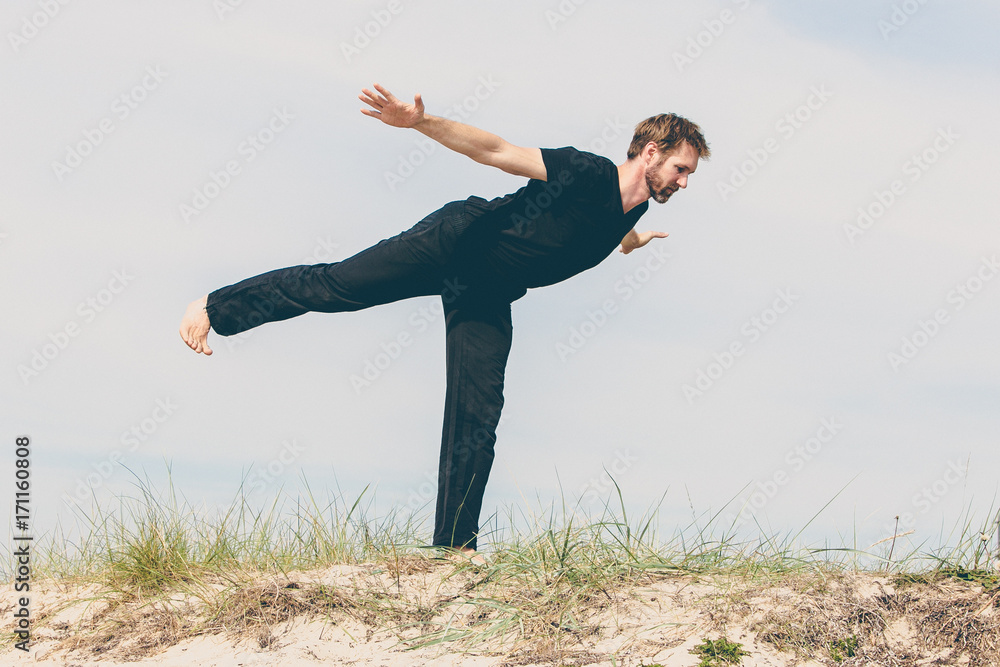 Junger Mann während seiner Yoga Übungen in den Dünen am Strand Junger Mann während seiner Yoga Übungen in den Dünen am Strand