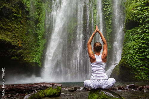 Woman meditating doing yoga between waterfalls