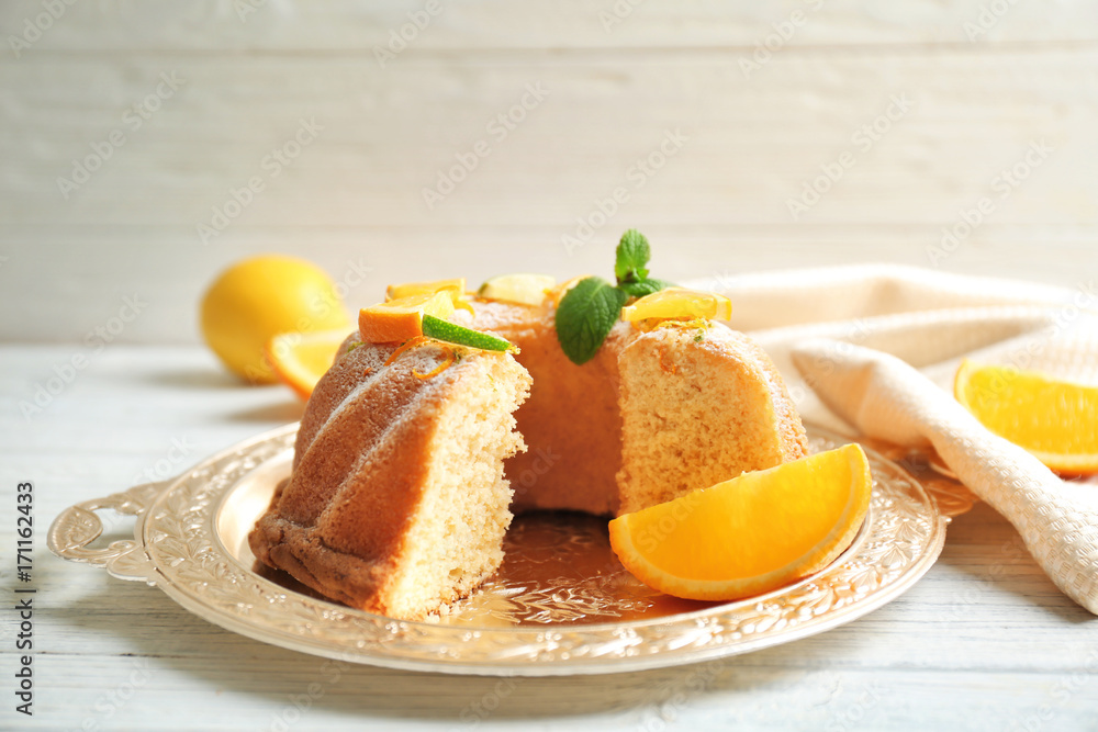 Tray with delicious sliced cake and citrus fruits on wooden table Tray with delicious sliced cake and citrus fruits on wooden table