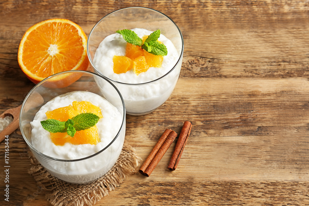 Creamy rice pudding with orange in glasses on wooden table Creamy rice pudding with orange in glasses on wooden table