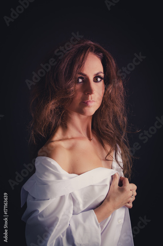 Young woman portrait in white shirt on black background. Mona lisa today.