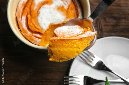 Spoon with tasty carrot souffle on blurred background photo