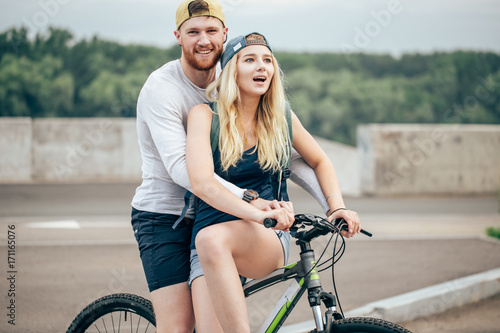 Happy man giving girlfriend a lift on his crossbar of bike on the beach photo