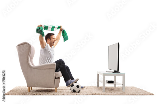 Excited soccer fan with a scarf sitting in an armchair photo