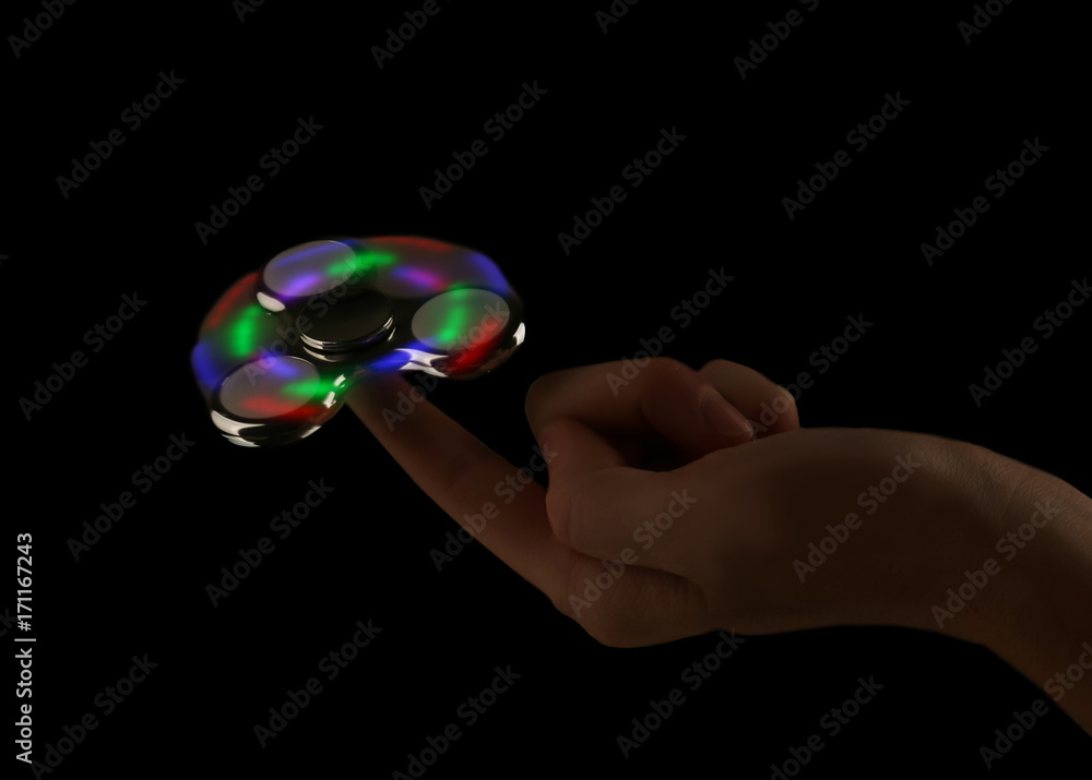 Man rolling modern luminous spinner on dark background Man rolling modern luminous spinner on dark background