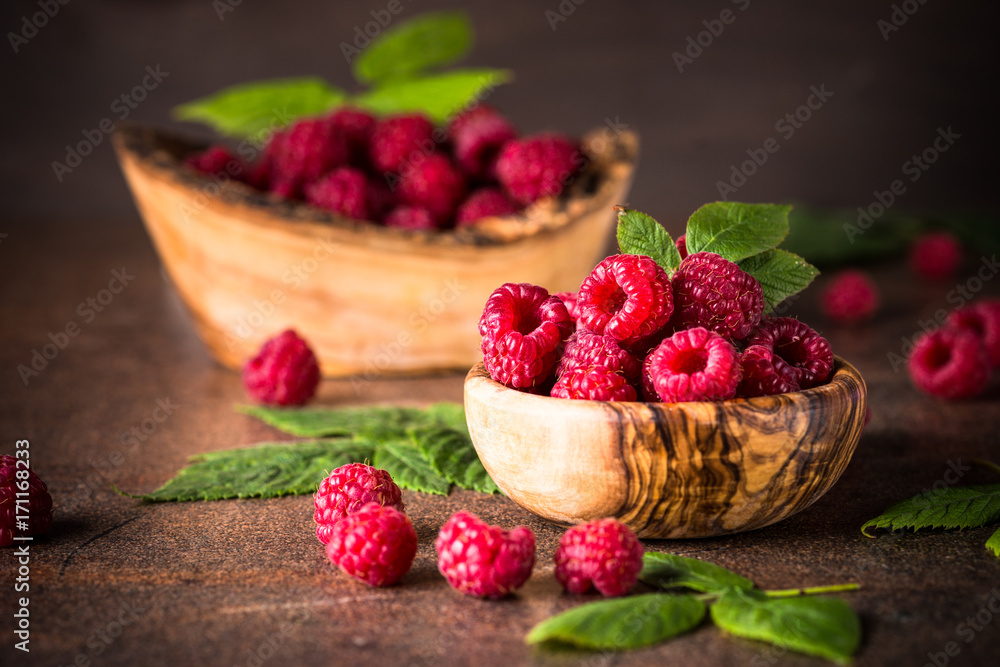 Fresh raspberries in wooden bowl on white table. Fresh raspberries in wooden bowl on white table.