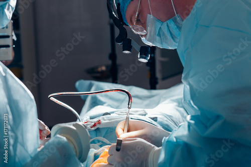 Фотография Close-up shot of surgeon and his assistant performing cosmetic surgery in hospit