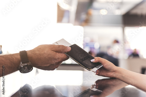 Male arm taking passport from young cashier