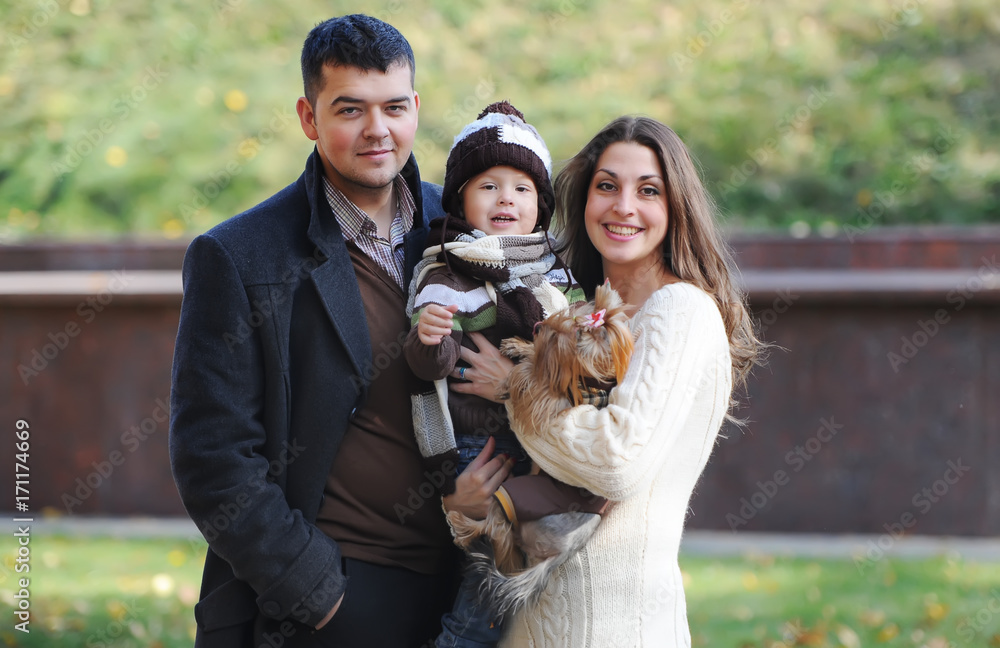Happy family of three standing together in the park in autumn Happy family of three standing together in the park in autumn