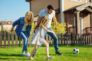 Cheerful family playing football on the backyard lawn