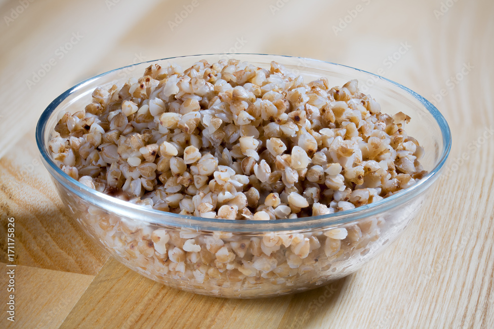 Boiled buckwheat porridge in a glass plate on a wooden table Boiled buckwheat porridge in a glass plate on a wooden table