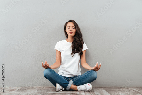 Beautiful young asian woman sitting in yoga position and meditating