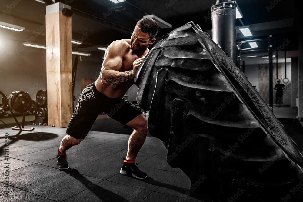 Photo & Art Print Shirtless man flipping heavy tire at crossfit gym