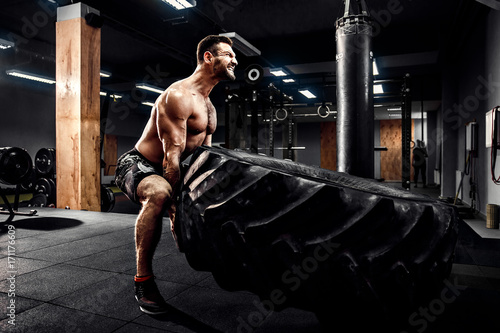 Fotografi Shirtless man flipping heavy tire at crossfit gym