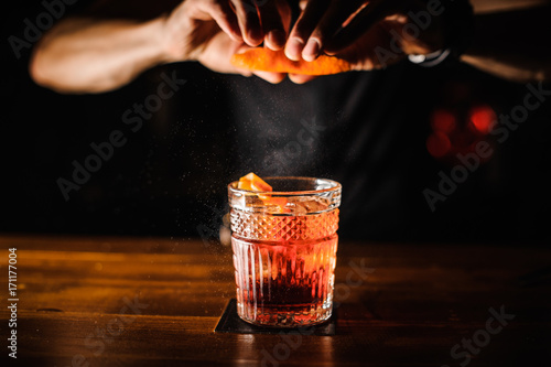 Obraz na plátně bartender with cocktail and orange peel preparing cocktail at bar