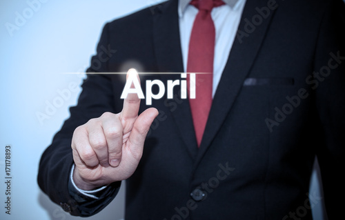 Businessman pressing button on virtual screen April button - concept