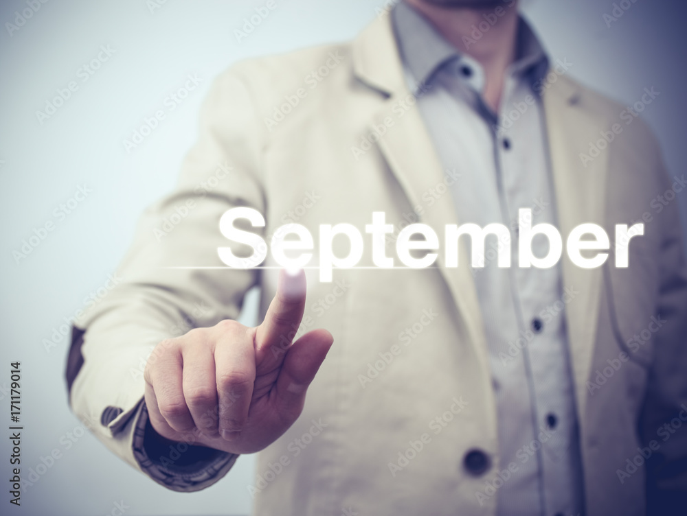 Businessman pressing button on virtual screen September button - concept Businessman pressing button on virtual screen September button - concept