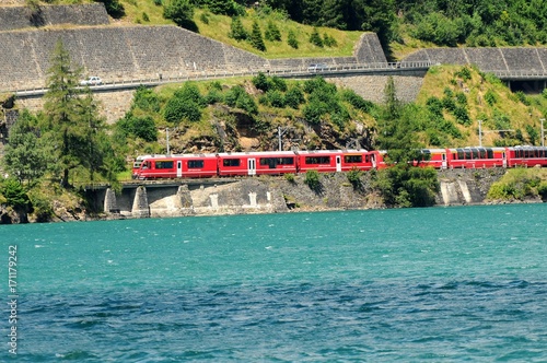 The famous Red Train Bernina Express running from St. Moritz to Tirano in Italy passing from Lake of Poschiavo