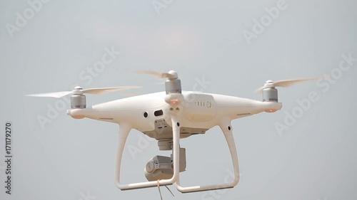 White quadrupter floats in the air, quadrocopter flies, propellers spinning, quadrocopter hovering over the ground photo