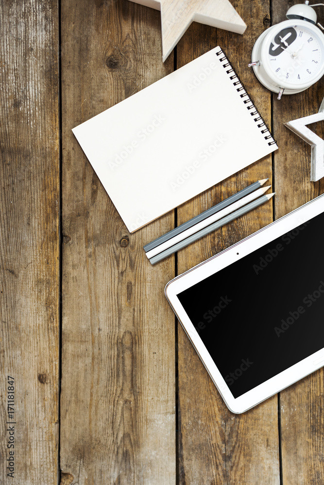 Modern conceptual wooden office or home desk table with tablet, note book, cup of pens, wooden star, businesscard and table clock. Place for typography and logo. Flat composition Modern conceptual wooden office or home desk table with tablet, note book, cup of pens, wooden star, businesscard and table clock. Place for typography and logo. Flat composition